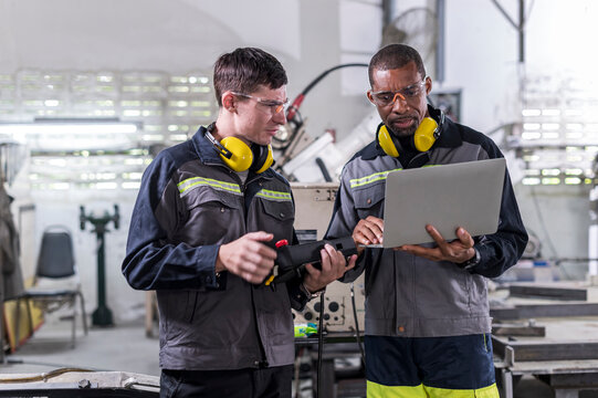 Robotics control engineers discussion and solve problems control panel of robot for setting programming for industrial robot arm controller in production plant factory