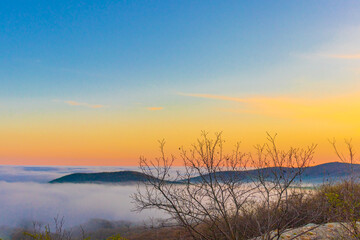 Mountain range with visible silhouettes through the morning colorful fog.