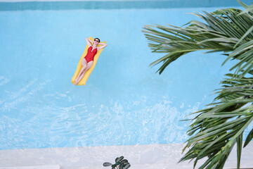 Enjoying suntan. Tropical vacation concept. Top view of young woman on the yellow air mattress in...