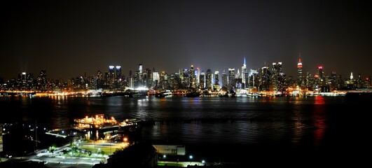 Fototapeta na wymiar Poster perfect New York city panoramic illuminated skyline. A view of New York city at night. The most populous city in the USA is home to the highest number of completed high rise buildings
