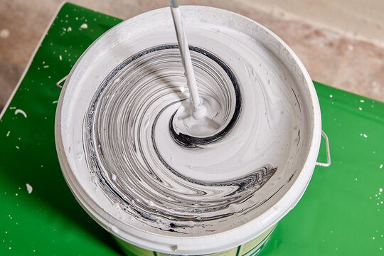 Mixing Two Colors Of Paint In Bucket, Spiral Pattern Is Formed On Surface Of Liquid.