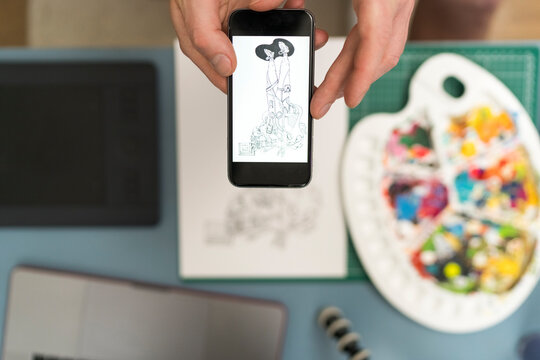 Artist taking design photo through mobile phone at home