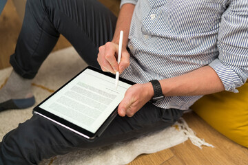 Businessman signing document over digital tablet while sitting at home