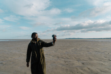 Male travel influencer vlogging at beach against sky