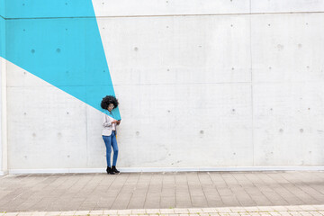 Young woman standing outdoors with smart phone in hands covered in blue facial recognition effect