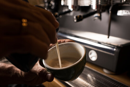Barista pouring milk while making coffee at cafe