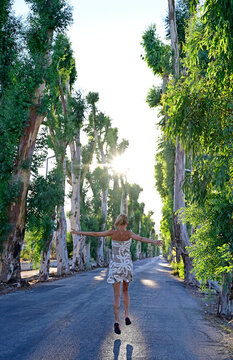 Greece, Dodecanese, Kolymbia, Adult woman hopping&Ocirc;&oslash;&Omega;merrily along eucalyptus avenue in summer