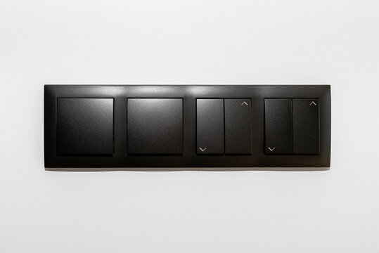 Black frame with a button to switch the lights and roller shutter up and down on the gray wall of the house.