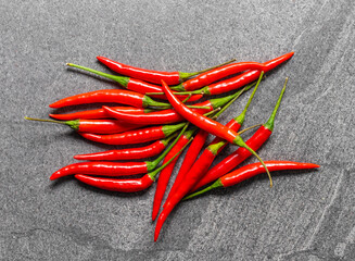 Several fresh Red hot chili pepper on a dark black stone background, food ingredient concept, top view.