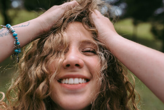 Smiling blond woman with hand in hair at park