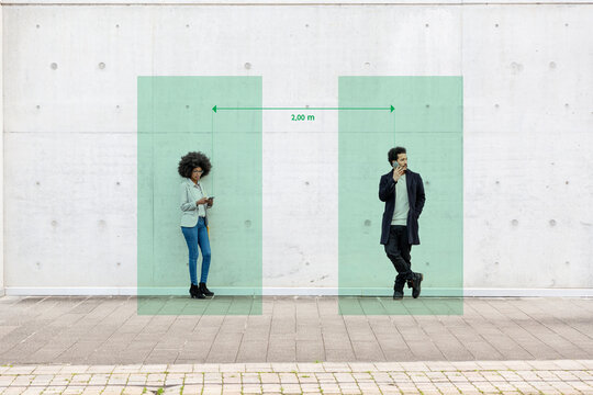 Rectangles visualizing social distancing covering man and woman standing outdoors with smart phones in hands