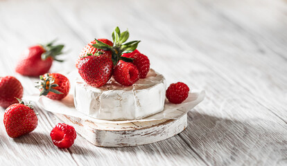 Camembert cheese with honey, raspberries, blueberries and strawberries. Healthy snack.