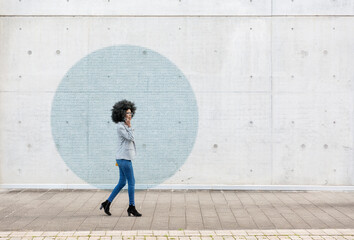 Visualization of data coming out of smart phone used by young woman walking along sidewalk