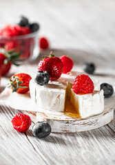 Camembert cheese with honey, raspberries, blueberries and strawberries. Healthy snack.