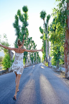 Greece, Dodecanese, Kolymbia, Adult woman hopping&Ocirc;&oslash;&Omega;merrily along eucalyptus avenue in summer