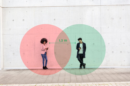 Two overlapping circles visualizing social distancing covering man and woman standing outdoors with smart phones in hands