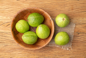 Red guavas on a bowl over wooden table