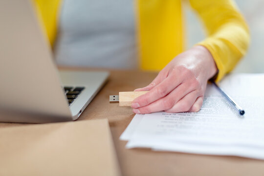 Woman connecting USB stick to laptop on table at home