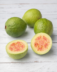 Red guavas and half fruits over wooden table