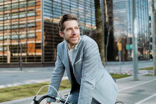 Smiling businessman on bicycle in city