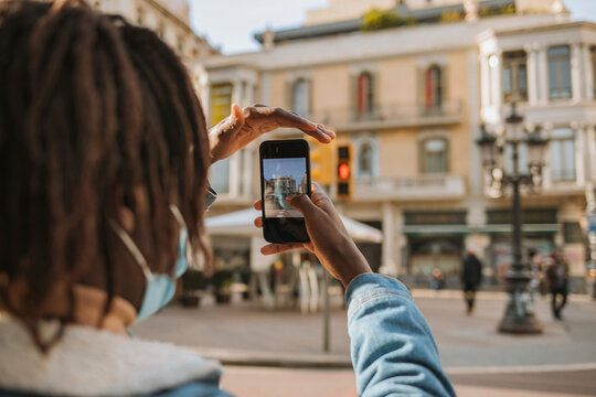 Young man photographing building in city during pandemic