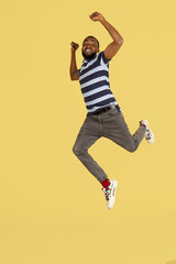 Fototapeta na wymiar One African young man jumping isolated over yellow studio background with copyspace for ad