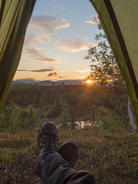 Mature male hiker in tent during sunset in forest at Sweden