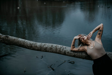 Young woman with eyes closed leaning on fallen tree against lake