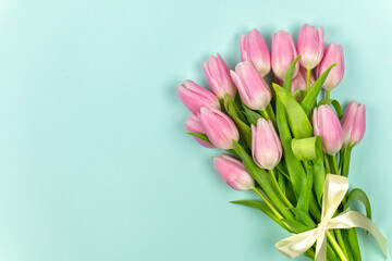 Bouquet of pink tulips with pastel colored ribbon on a mint background. Mother's Day, Easter, Valentine's Day. Spring flowers. Copy space. Top view