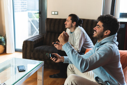Cheerful friends playing video game in living room at home