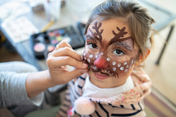Cute girl with painted face at home during Christmas