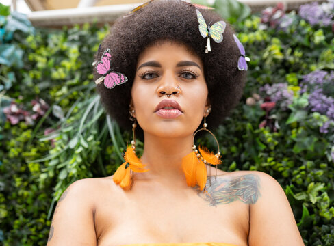 Female Hipster With Butterfly Hair Clip Against Plants