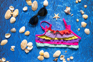 accesories for summer sea beach on blue wawes background. Beach things sunglasses and swim suit