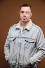 Vertical shot Portrait of an attractive young man in the studio on a brown background. Well-groomed contented smiling nice guy looking at the camera