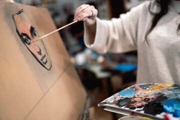 Female artist painting face on canvas at art studio