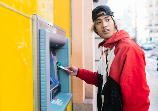 Asian man withdrawing money from ATM machine