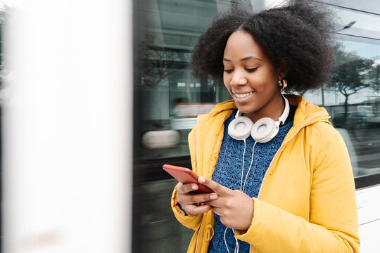 Young woman text messaging on smart phone while standing by tram