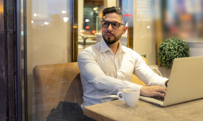 Male entrepreneur looking away while using laptop in cafe