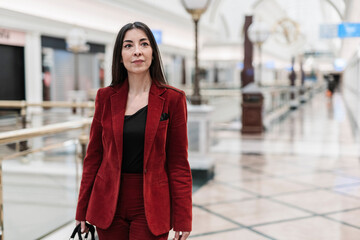 Confident mature businesswoman in red blazer walking at subway station