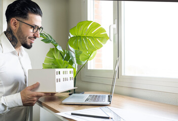 Smiling design professional showing architectural model during video call through laptop at desk