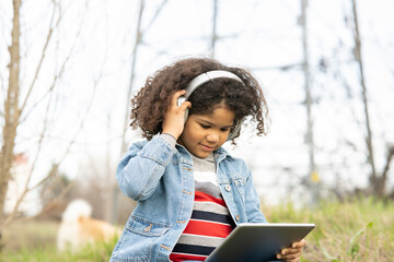 Boy listening through headphones while using digital tablet in nature