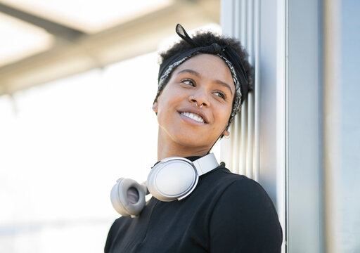 Young woman looking away while leaning on wall