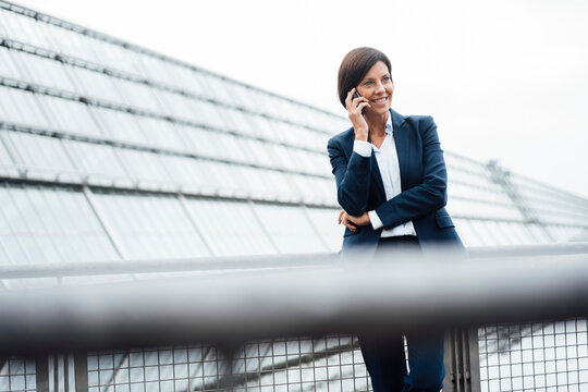 Female entrepreneur talking on smart phone outside office building