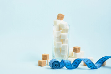 measuring tape and cubes of white and brown sugar in a glass copy space, sugar in drinks and food concept