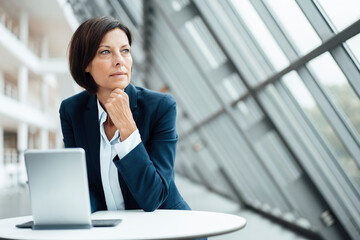 Female professional contemplating by digital tablet in corridor
