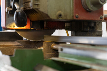close up view of a steel saw and blade cutting metal in a metal worker shop