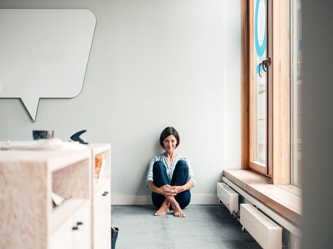Smiling female entrepreneur with hands clasped in office