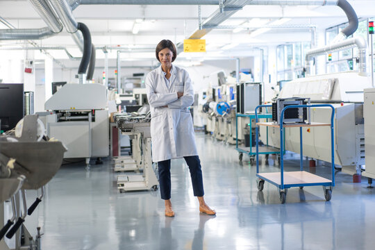 Confident female engineer with arms crossed standing in industry