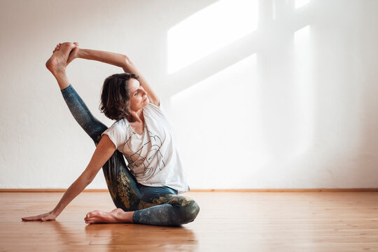 Woman practicing yoga in front of white wall at health studio