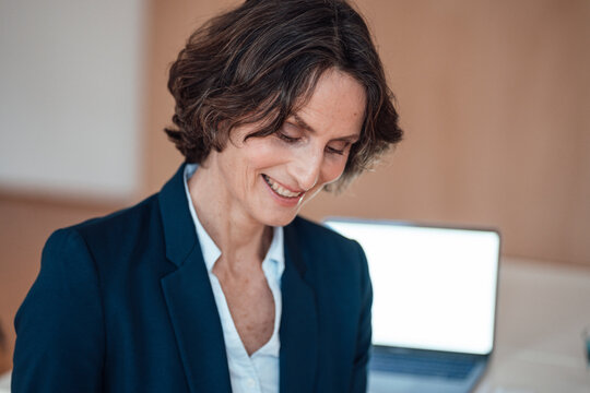 Smiling mature businesswoman looking down in home office